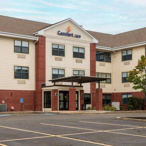 A Comfort Inn hotel building with a brick facade, a covered entrance, and a parking lot in front.