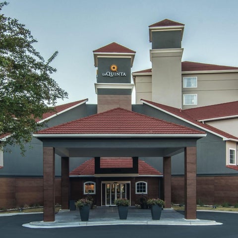 A La Quinta Inn & Suites building features a distinctive tower and red-roofed entrance with a covered walkway.