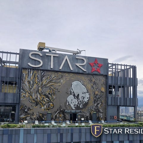 A building facade of Star Residence features a large mural and rooftop terrace with lounge chairs and a pool.