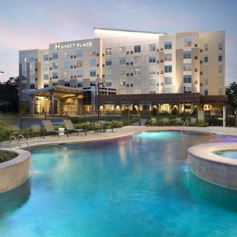 A Hyatt Place features a lit outdoor pool with lounge chairs and a modern building facade in the background.