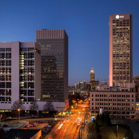 An evening cityscape shows several illuminated skyscrapers and city streets with traffic in Oklahoma City.