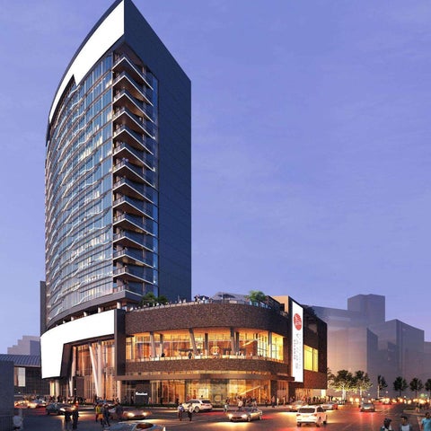 A modern high-rise building with a curved base and glass facade stands prominently on a city street at dusk.