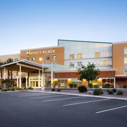 A Hyatt Place hotel building features a modern facade with a covered entrance, parking lot, and landscaping.