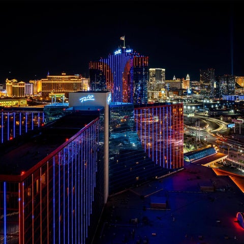 A nighttime aerial view showcases a brightly lit casino resort complex with illuminated buildings and a prominent tower.