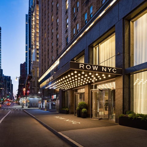 The Row NYC hotel's entrance features a prominent marquee sign and glass doors on a bustling New York City street.
