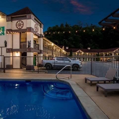 A hotel building with a pool and lounge chairs is visible at dusk, featuring a unique architectural design.