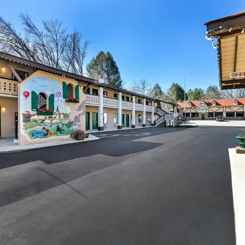 A motel building facade with a painted mural, parking lot, and office area under a covered entrance.